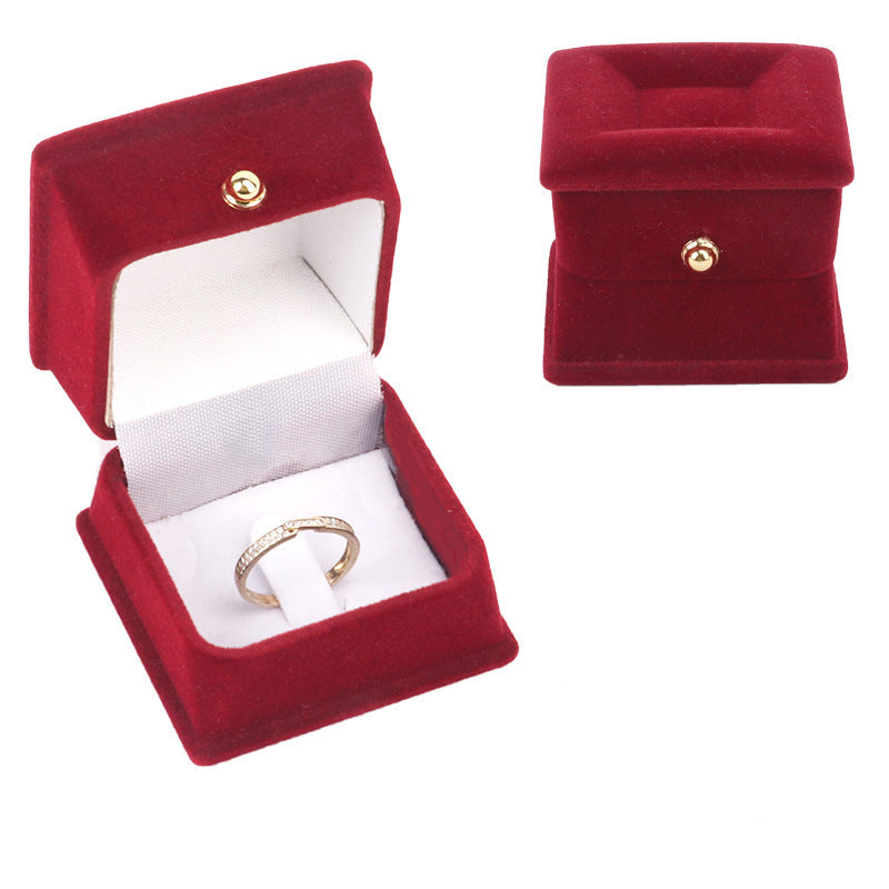 Red velvet jewelry box with a gold ring inside on a white background